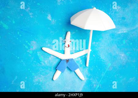 Fröhlicher weißer Seesterne-Charakter, der auf hellblauem Hintergrund mit einem weißen Sonnenschirm in der Hand schwimmt. Positives Urlaubskonzept auf See. Stockfoto