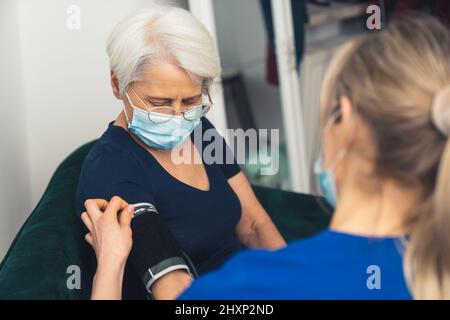 Erwachsene Rentnerin und Pflegekraft sitzen während des Hausbesuches zusammen. . Hochwertige Fotos Stockfoto