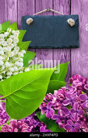 Fliederblüten und Maiglöckchen mit leerem Schild auf Holzgrund Stockfoto