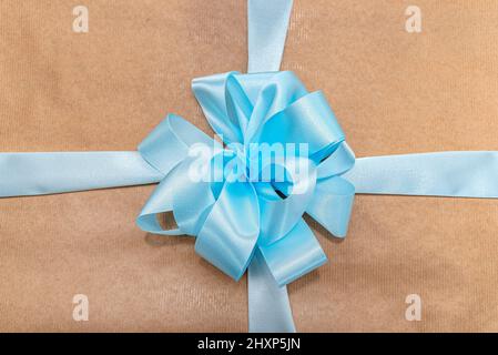 Ein Geschenk in graues Papier verpackt mit einem blauen Band in einer Schleife gebunden, Nahaufnahme. Stockfoto