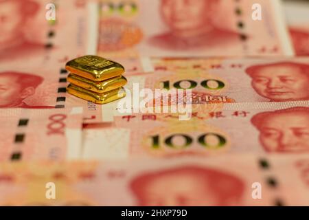 Stapel von reinen Goldbarren, Goldbarren, Barren auf dem Hintergrund von Renminbi oder RMB, CNY, Währung von China. Satz von einhundert Yuan. Chinesisches Geld. Geschäftskontra Stockfoto