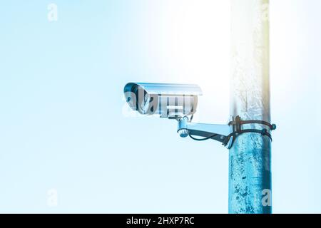 Digitale CCTV-Kamera auf einem Metallmast, blauer pastellfarbener Hintergrund. Sicherheitskameras schützen die Straßen für Menschen. Stockfoto