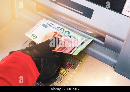 Frau Hand abheben Geld von der Bank im Freien Geldautomaten. Weibliche Hand, die Euro-Banknoten aus dem Bankautomaten nimmt. Stockfoto