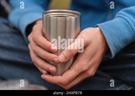 Isolierter Edelstahlbecher in den Händen Stockfoto