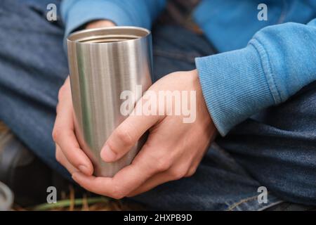 Isolierter Edelstahlbecher in den Händen Stockfoto