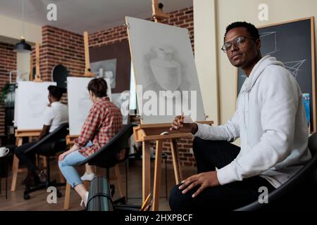 Porträt eines lächelnden Malers Schüler attesting Zeichnung Klasse entwickeln neue künstlerische Fähigkeiten für persönliches Wachstum. Vielfältiges Team skizziert Vasenmodell arbeitet in der grafischen Technik. Kreatives Konzept Stockfoto