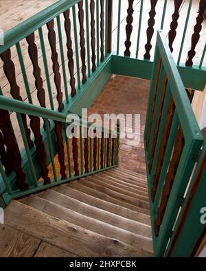 Blick von oben auf alte Holztreppe mit grünen und braunen Holzgeländern Stockfoto