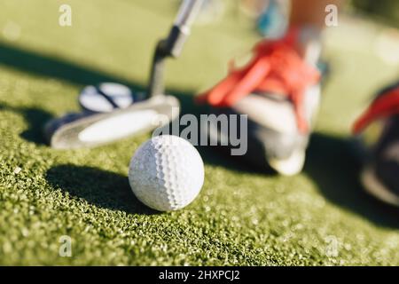 Kinder spielen Minigolf. Nahaufnahme des Spielers in Snickers mit Mini-Golf-brassy und weißen Golfball Stockfoto