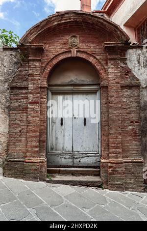 Gut erhalten und aufwendig dekoriert bescheidene alte Eingangstür in der Toskana, Italien Stockfoto