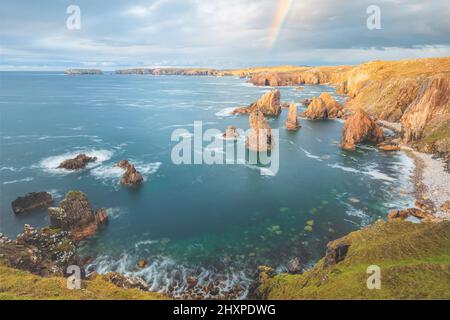 Golden Hour Licht und Regenbogen über dramatische felsige Landschaft Seeseite der Mangersta Sea Stacks an der Küste der Isle of Lewis in den Äußeren Hebriden o Stockfoto