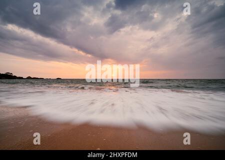 Wunderschöner Sonnenuntergang über dem Indischen Ozean. Lange Exposition von Meereswellen auf leeren Sandstrand in Sri Lanka. Stockfoto