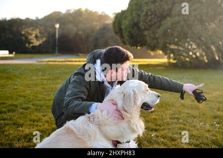 Kaukasischer Junge mit goldenem Retriever-Hund in einem grünen Park, der auf etwas zeigt Stockfoto