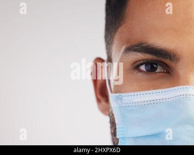 Trage deine Maske, weil niemand unbesiegbar ist. Ausgeschnittene Aufnahme einer nicht erkennbaren Krankenschwester, die allein im Studio steht und eine Gesichtsmaske trägt. Stockfoto