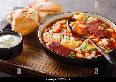 Babgulyas ungarische Suppe mit Bohnen, Fleisch und Gemüse in der Nähe in den Teller auf dem Holztablett. Horizontal Stockfoto