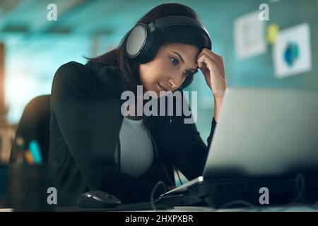 Auf der Bank, weil ich nicht fliegen kann. Porträt einer erschöpften jungen Frau, die in einem modernen Büro ein Headset benutzt. Stockfoto