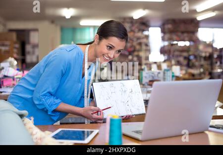 Was denken Sie also? Eine junge Designerin, die ihre Entwürfe während einer Videokonferenz jemandem zeigt. Stockfoto