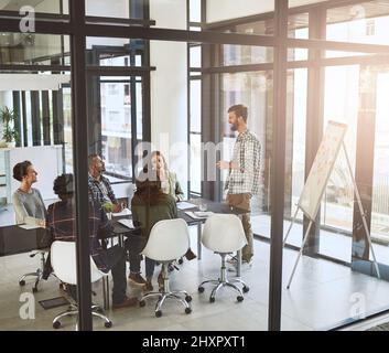 Gemeinsam neue Ideen entwickeln. Aufnahme eines Geschäftsmannes, der seinen Mitarbeitern in einem modernen Büro eine Präsentation gibt. Stockfoto