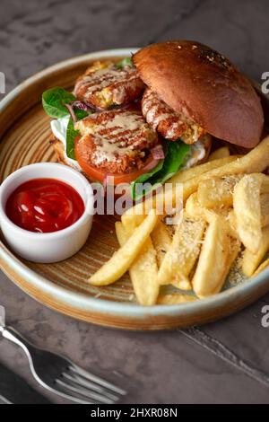 Falafel-Burger mit Salat, Tomaten, Zwiebeln, pommes frites, würzig duftender Sauce auf dem Tisch. Vegetarisches Essen lecker und nahrhaft. Stockfoto