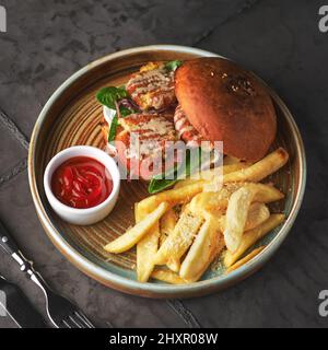 Falafel-Burger mit Salat, Tomaten, Zwiebeln, pommes frites, würzig duftender Sauce auf dem Tisch. Vegetarisches Essen lecker und nahrhaft. Stockfoto