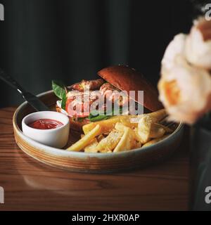 Falafel-Burger mit Salat, Tomaten, Zwiebeln, pommes frites, würzig duftender Sauce auf einem Holztisch. Vegetarisches Essen lecker und nahrhaft. Stockfoto