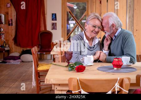 Ein älteres, romantisches Paar, das seinen Hochzeitstag im Restaurant feiert. Stockfoto