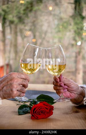 Die Hände eines romantischen Paares toasten mit Gläsern Wein. Stockfoto
