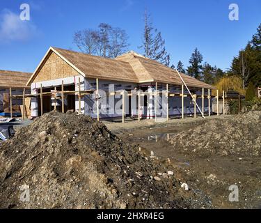 Ein Holzhaus im Bau in einer neuen Unterteilung vor einem leeren Grundstück. Stockfoto