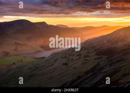 Spektakulärer Sonnenuntergang im Lake District mit wunderschönen leuchtenden Lichtstrahlen, die auf die Berge und das Tal von Buttermere scheinen. Zerklüftete britische Landschaft. Stockfoto