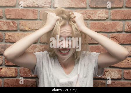 Eine Frau in Depressionen reißt ihr die Haare. Probleme der Frauen, Stress, Ärger. Stockfoto