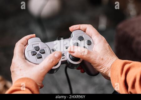 Nicht erkennbare Frau, die Videospielkonsole spielt. Reife kaukasische Frau spielt Videospielkonsole. Stockfoto