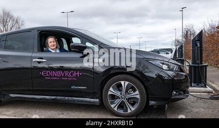 Ingliston Park & Ride, Edinburgh, Schottland, Großbritannien, 14. März 2022. Ingliston Park & Ride Elektroauto-Ladebuchten: Transport-Convener und Stadträtin der Stadt Edinburgh, Lesley MacInnes, sieht, wie neue Ladegeräte mit einem City of Edinburgh Council Elektroauto am Park and Ride funktionieren. Fünfzehn neue 7kwh Ladegeräte wurden installiert, um 30 weitere Elektrofahrzeuge als Teil der £2,2m-Einführung des Rates in der ganzen Stadt unterzubringen. Stockfoto