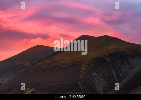 Leuchtend rosa und lila Sonnenuntergang leuchtenden Himmel über Lake District Bergkette an einem schönen Sommerabend. Stockfoto