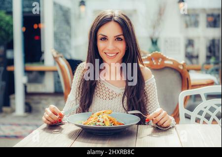 Die junge Frau genießt das Essen in einem Restaurant und macht ihre Mittagspause. Nahaufnahme Stockfoto