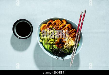 Vegane Sushi-Schüssel mit gebackenen Süßkartoffeln, Edamame-Bohnen, Avocado und Saftsauce. Gesunde Alternative Stockfoto