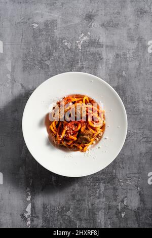 Hausgemachte Spaghetti mit Tomatensauce, Parmesan und Fleischbällchen auf dunklem Hintergrund Stockfoto