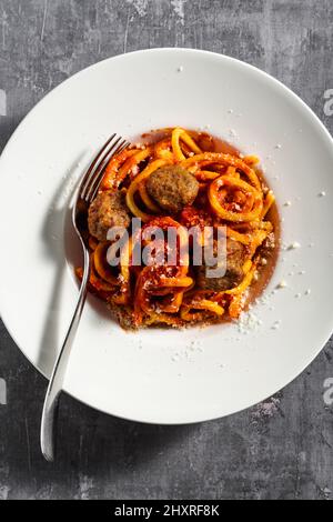 Hausgemachte Spaghetti mit Tomatensauce, Parmesan und Fleischbällchen auf dunklem Hintergrund Stockfoto