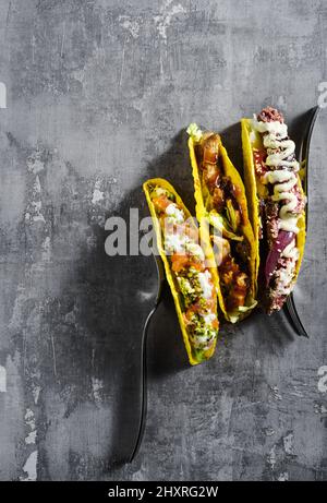 Set von Mais-Tacos mit Fisch und Fleisch auf einem Betontisch Stockfoto