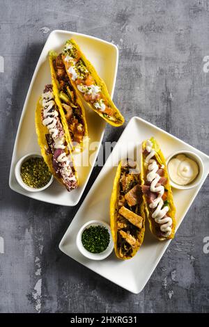 Set von Mais-Tacos mit Fisch und Fleisch auf einem Betontisch Stockfoto