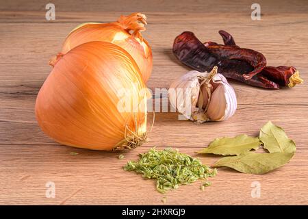 Holzbrett mit Zwiebeln, getrocknetem Chili, Knoblauch, Thymian und Lorbeerblättern Stockfoto