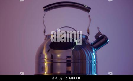 Silberner Wasserkocher aus Edelstahl auf rosa Wandhintergrund. Aktion. Nahaufnahme des neuen Elektrokessels, langsam drehend, Konzept der Haushaltsgeräte. Stockfoto