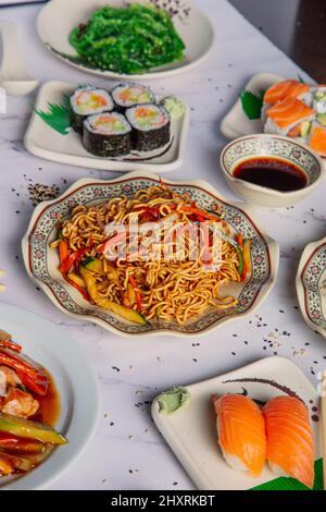 Auf dem Restauranttisch werden verschiedene asiatische Gerichte serviert. Stockfoto