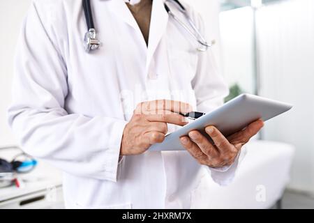 Einfache Aufzeichnung von Patientendaten. Ausgeschnittene Aufnahme eines männlichen Arztes mit einem digitalen Tablet in einem Krankenhaus. Stockfoto