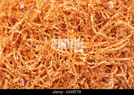 Orange/gelbe Farbe geschreddertes Papier - Geschenkbox Füllstoff Hintergrund. Stockfoto