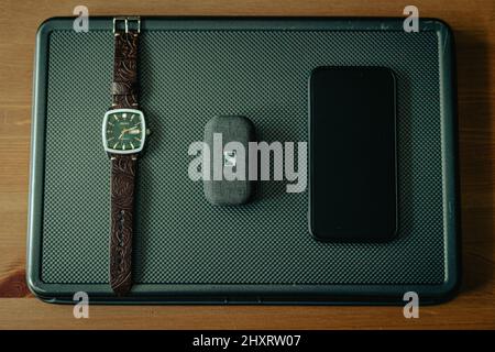 Draufsicht auf eine Seiko-Uhr, ein iPhone und kabellose Ohrhörer auf dem Display Stockfoto