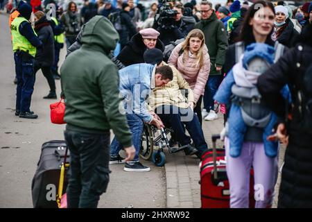 6. März 2022, Medyka, Polen: Flüchtlinge sehen, wie sie ihren behinderten Verwandten auf einem Rollstuhl tragen. Polnisch-ukrainischer Grenzübergang in Medyka. Seit Beginn der russischen Invasion in der Ukraine sind über 1,7 Millionen Menschen nach Polen geflohen, um dem Krieg zu entkommen. Ukrainische Flüchtlinge werden mit komplexer Unterstützung sowohl von Wohltätigkeitsorganisationen als auch von einfachen Polen begrüßt, aber viele humanitäre Experten weisen darauf hin, dass bei einem so großen Zustrom von Menschen und nicht ausreichender Unterstützung durch die polnische Regierung innerhalb weniger Wochen eine Krise eintreten könnte. (Bild: © Filip Radwanski/SOPA Images via ZUMA Press Wire) Stockfoto