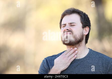 Überwältigter Mann mit Halsschmerzen in der Natur Stockfoto