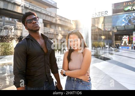 Frau lacht, während sie neben einer afrikanischen Freundin in einem Einkaufszentrum posiert Stockfoto