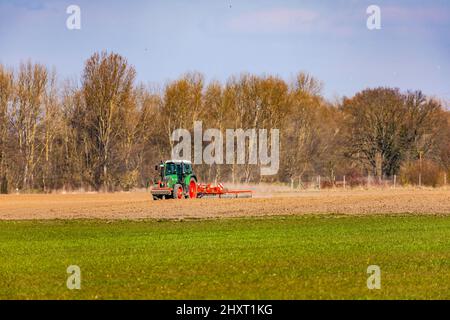 Ländliche Szene mit einem Traktor, der in der Wintersonne ein Feld mit einem Pflug pflügt Stockfoto
