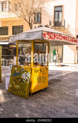 Athene Greece - Murch 2022: Griechischer runder Sesambagel koulouri Straßenverkauf. Koulouri Thessalonikis Zeichen auf Griechisch von Straßenhändler tragbarer Push-Cart se Stockfoto