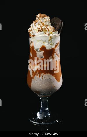 Vertikale Aufnahme eines Karamell-Milchshake auf schwarzem Hintergrund. Stockfoto